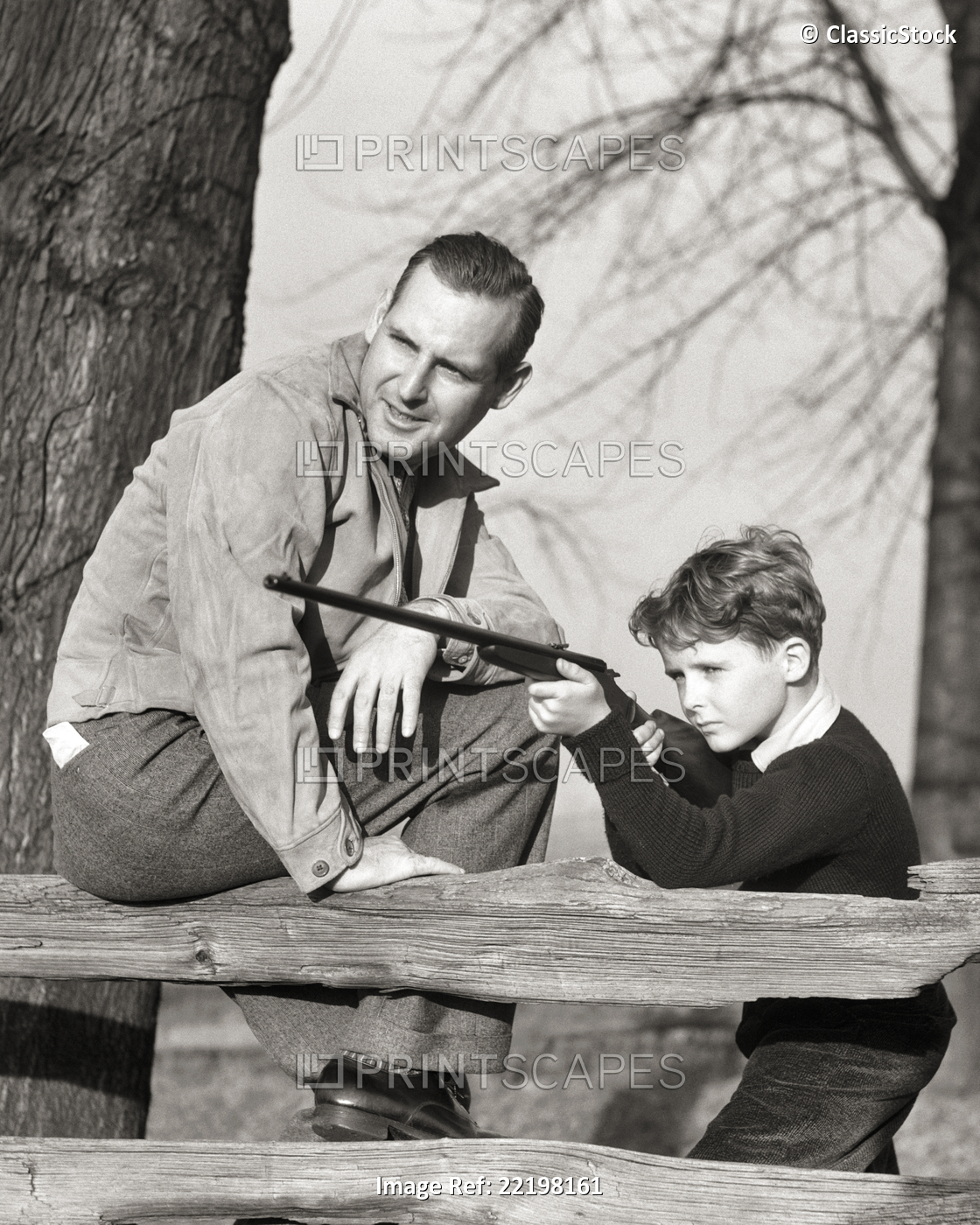 1930S FATHER TEACHING SON FIREARM FUN SAFETY BOY AIMING RIFLE OVER A WOODEN ...