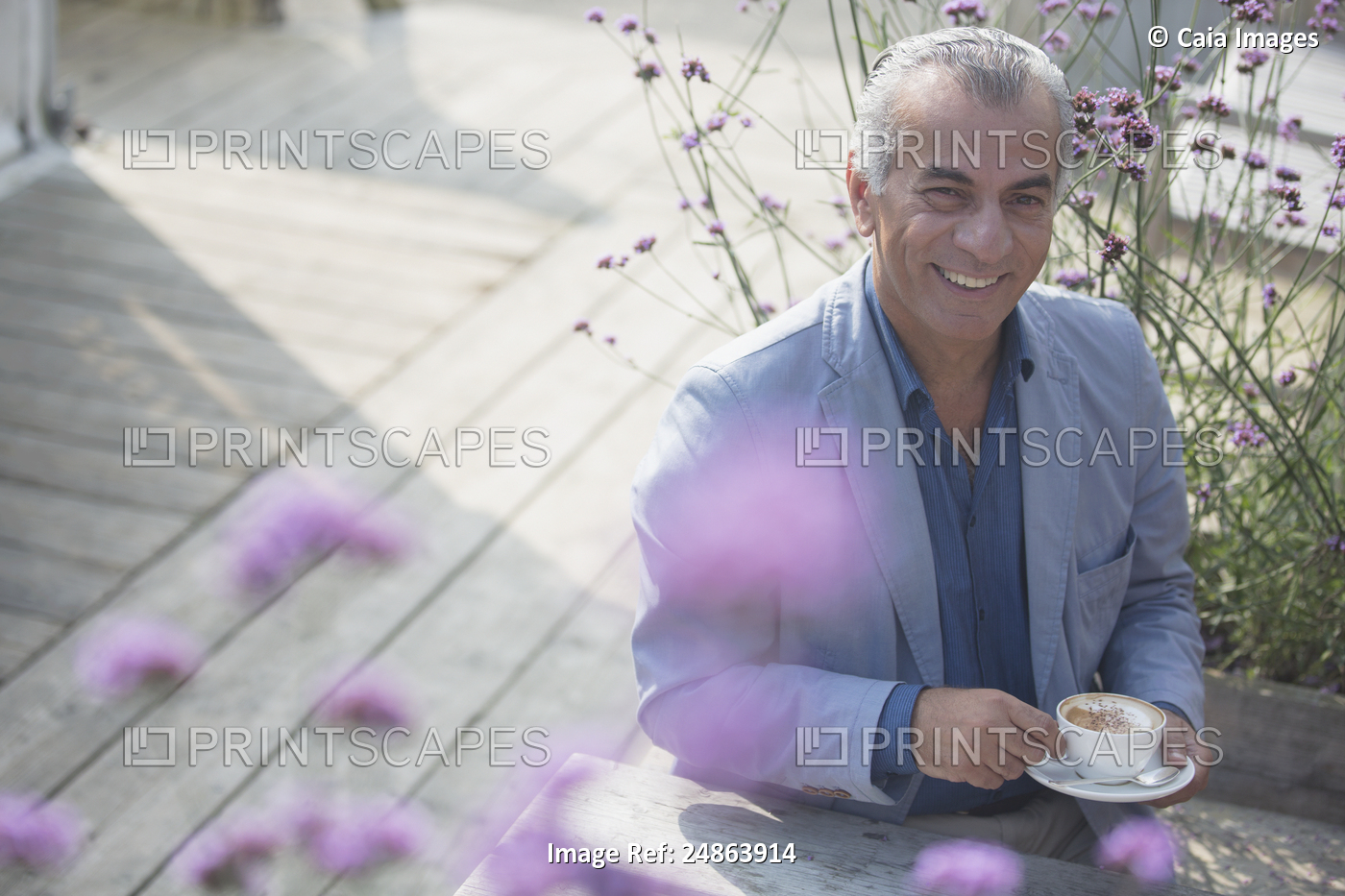 Portrait smiling senior man drinking coffee on sunny patio