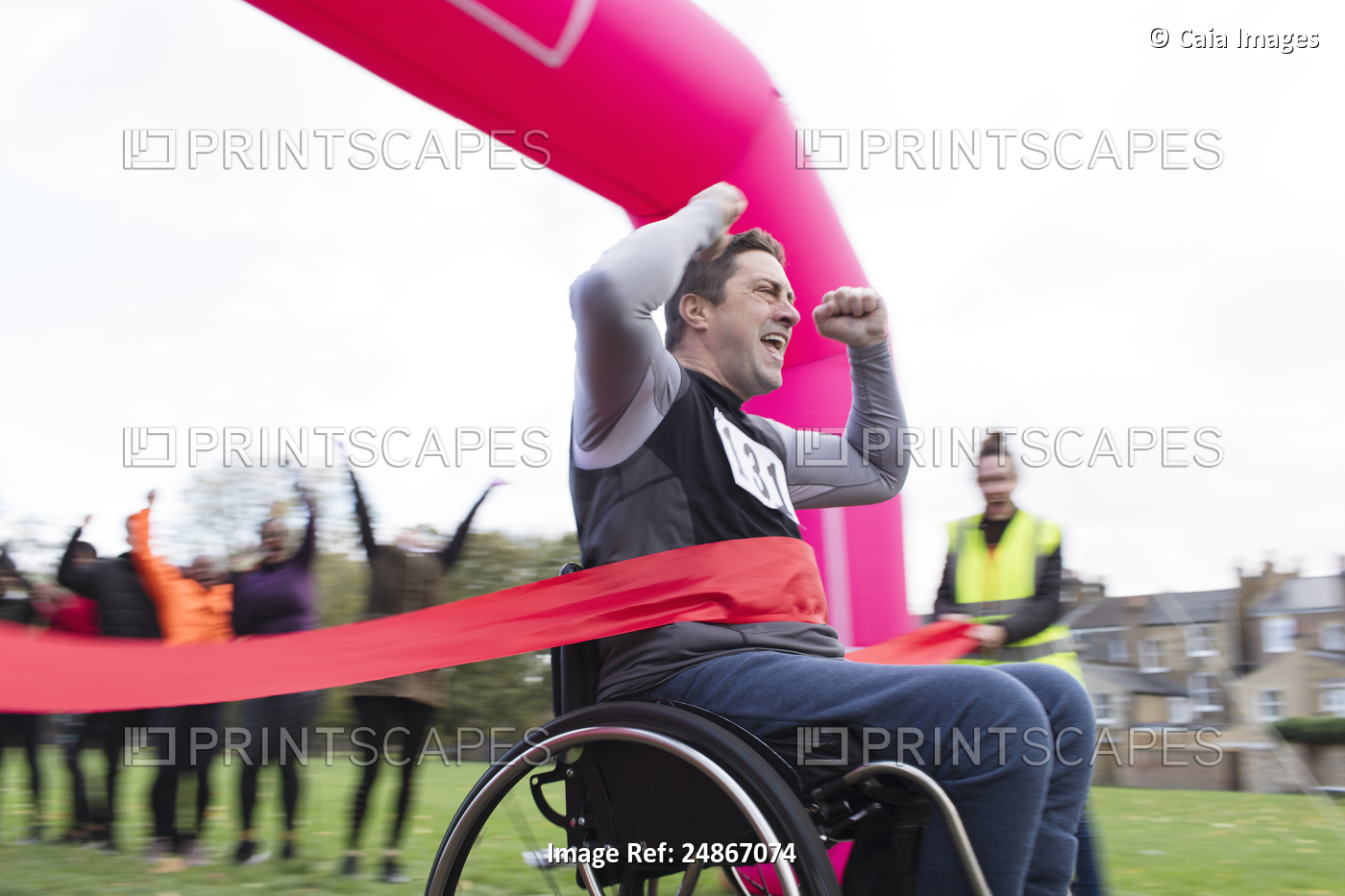 Enthusiastic man in wheelchair crossing finish line, cheering at charity race ...