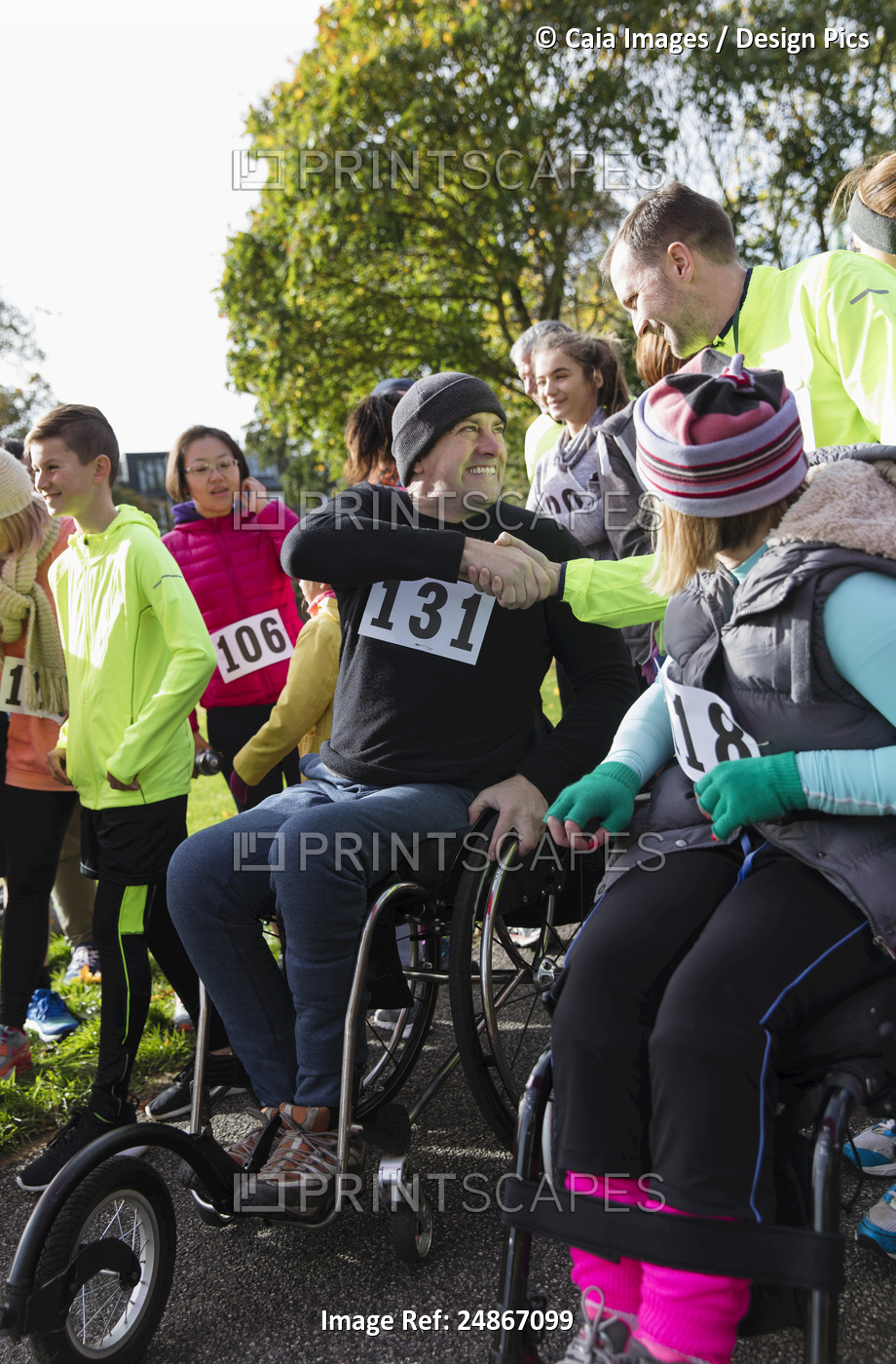 Man in wheelchair shaking hands with runner in crowd at charity race