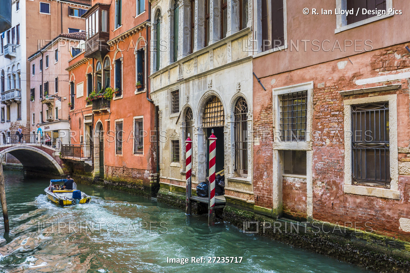 Motorboat travelling along a canal lined with historical buildings in Venice, ...