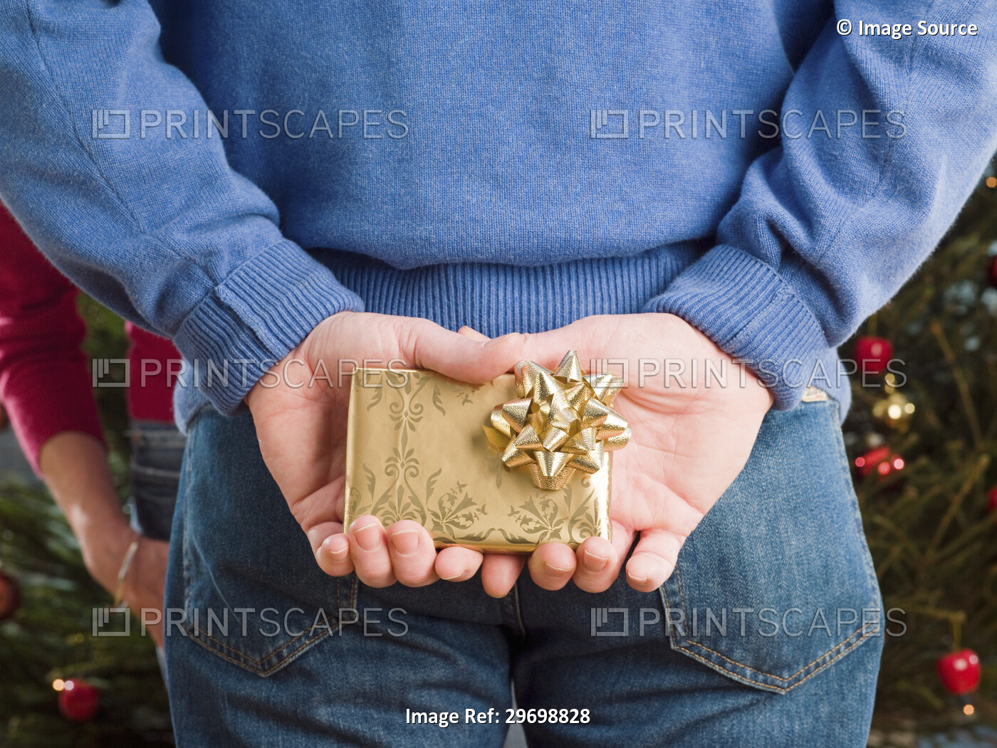 Man hiding a christmas present behind back