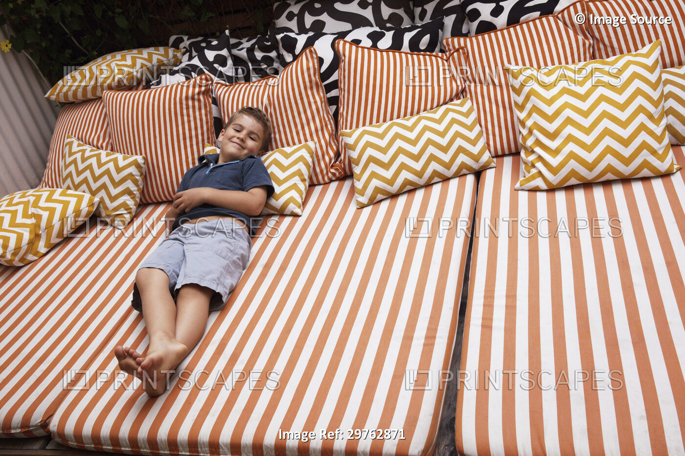 Boy relaxing on striped outdoor  furniture with cushions