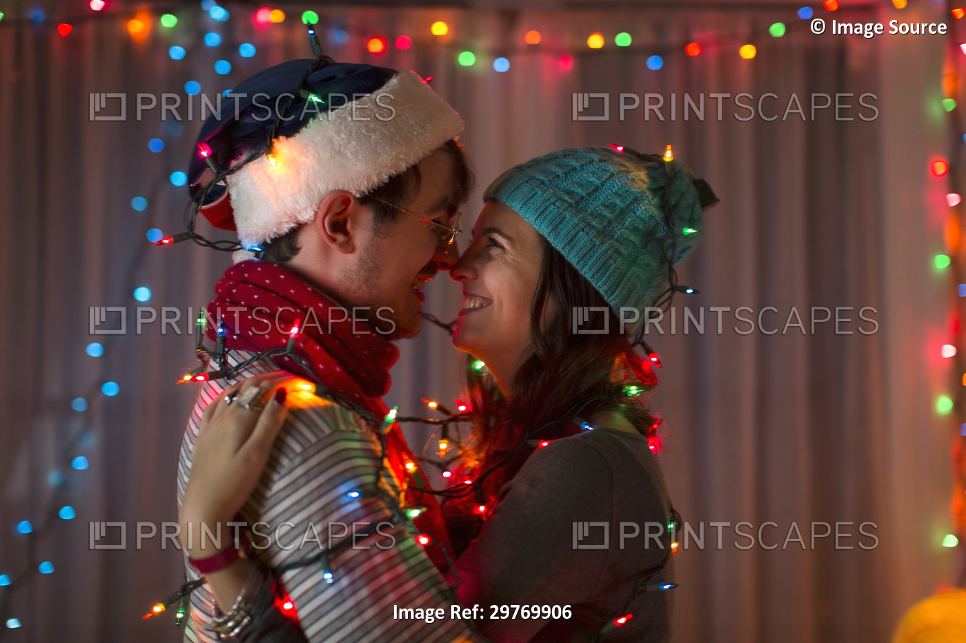 Romantic young couple wrapped in decorative lights at christmas