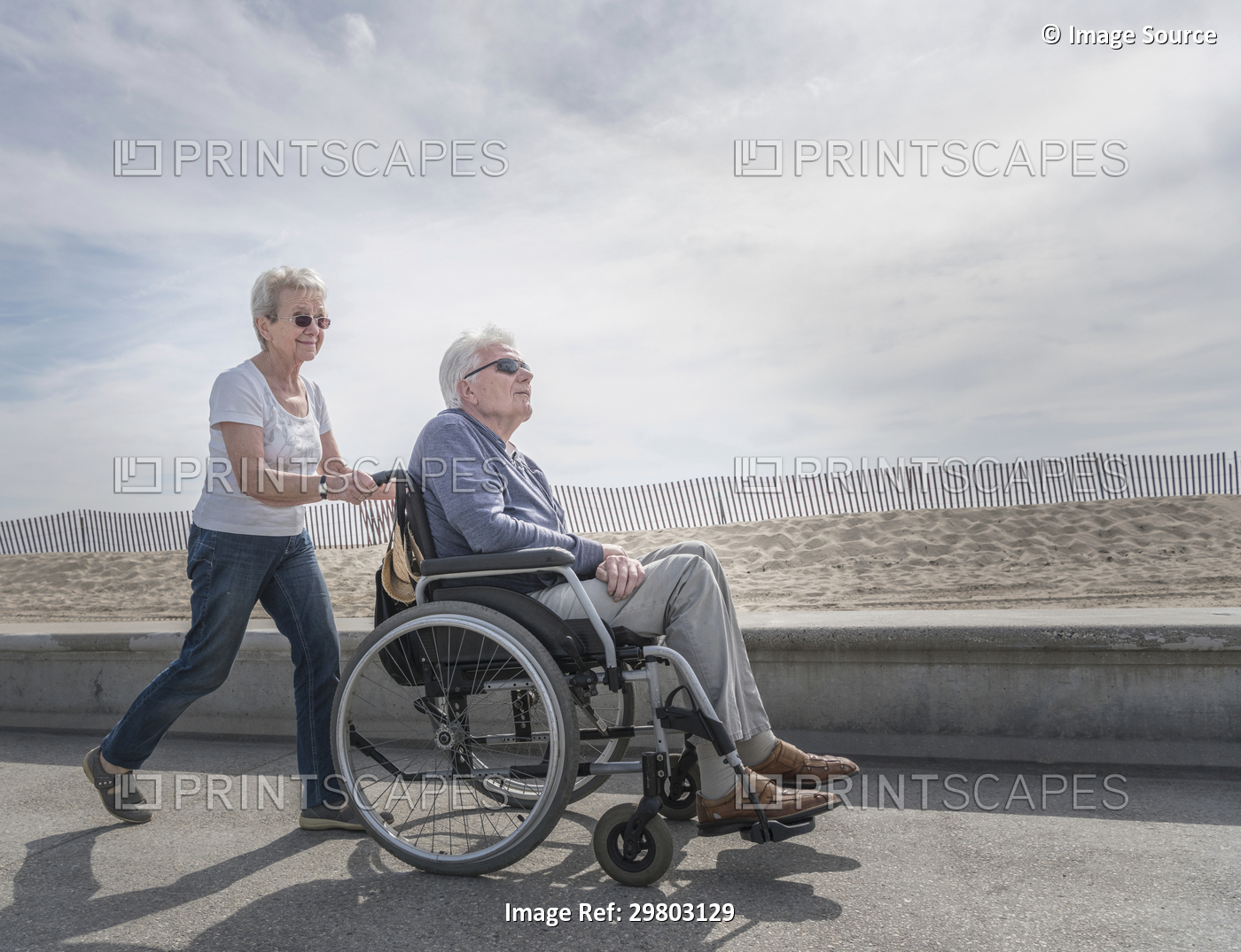 Senior woman pushing husband in wheelchair at beach, Santa Monica, California, ...