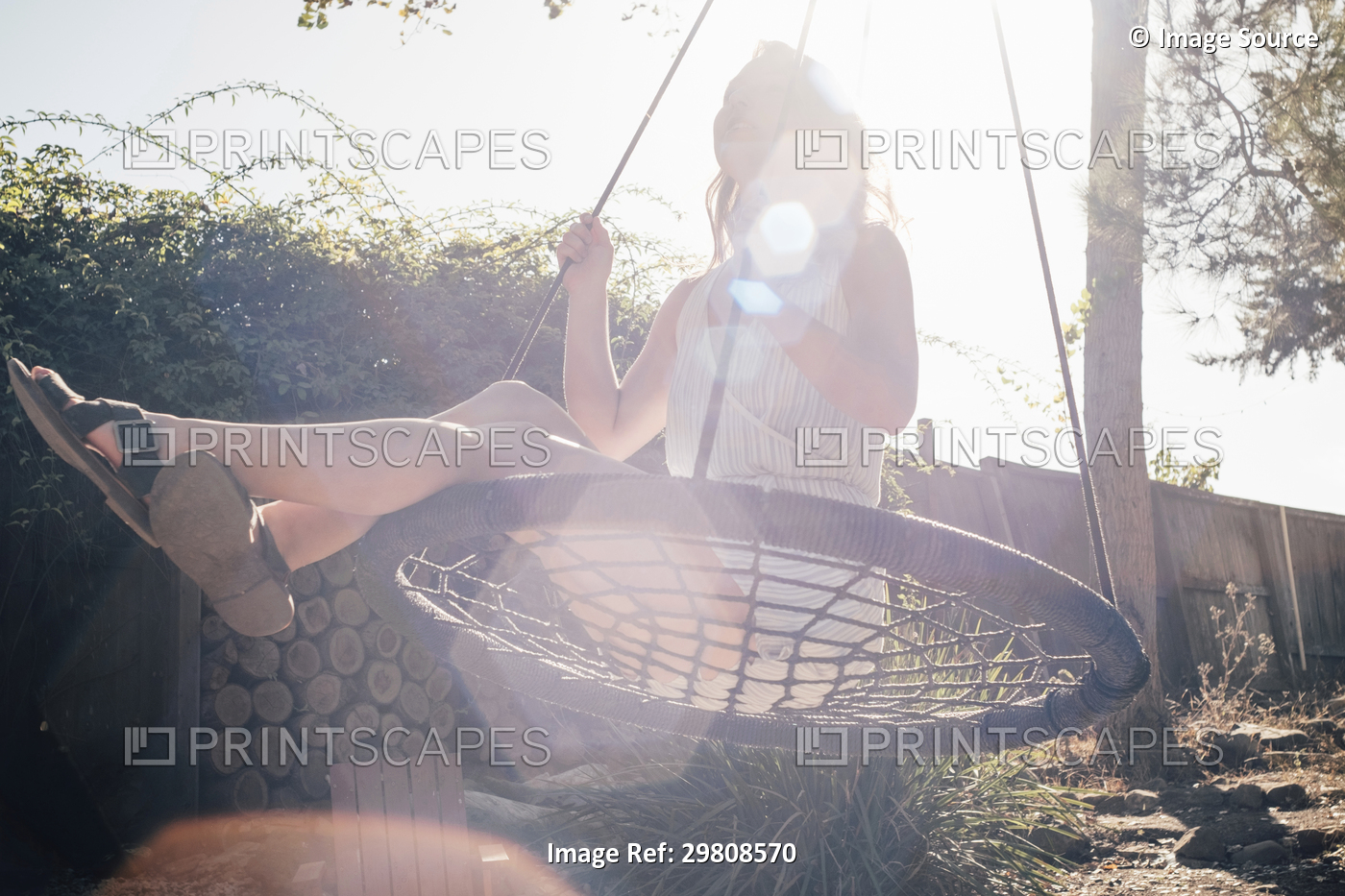Young woman swinging on garden swing, low angle view