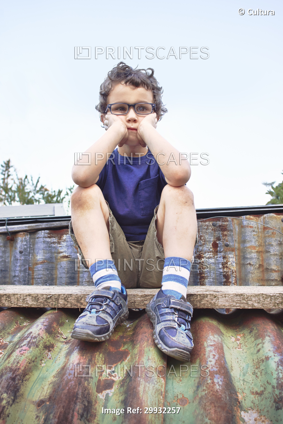Glum little boy sitting on roof