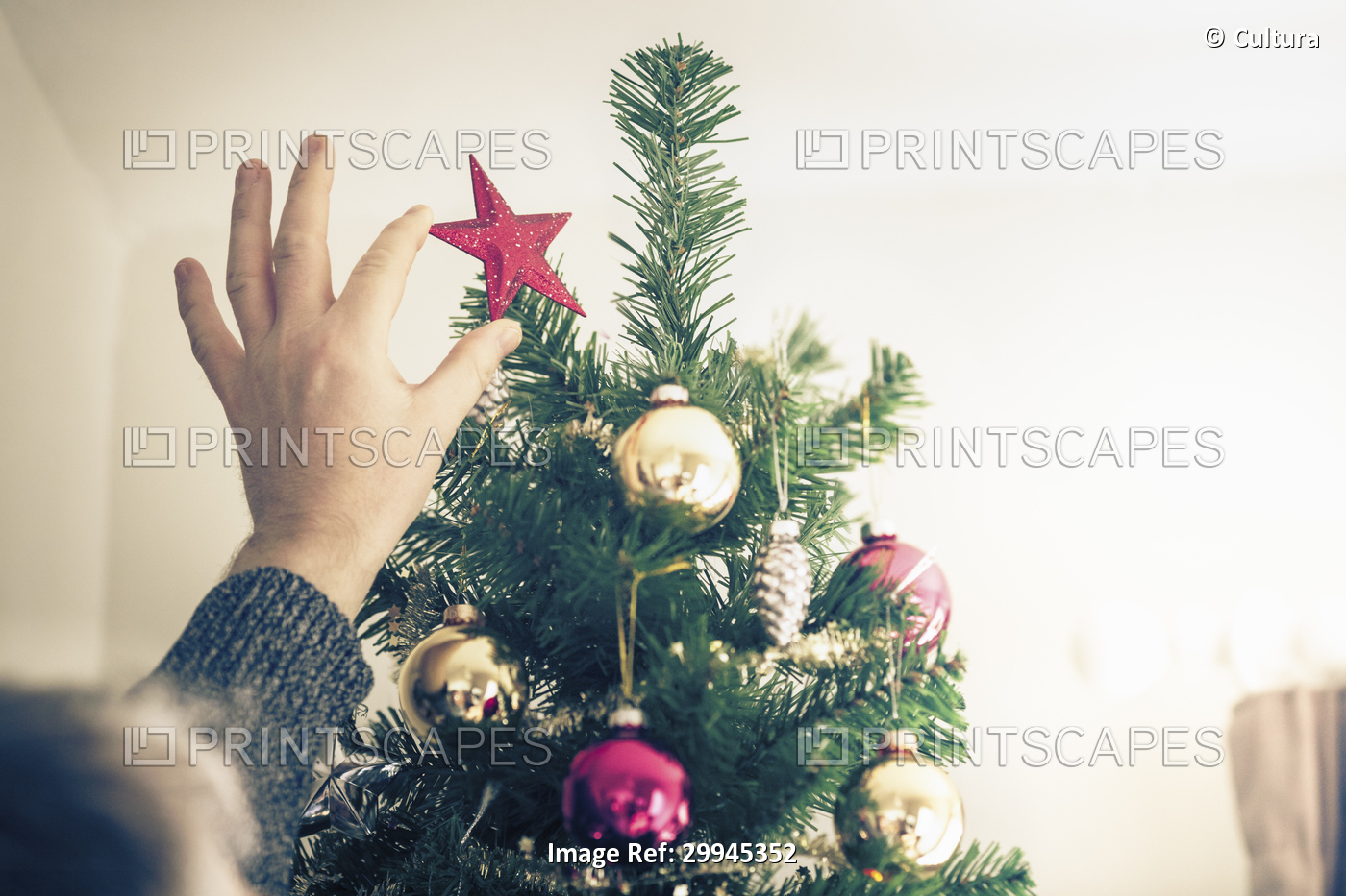 Person putting star on christmas tree