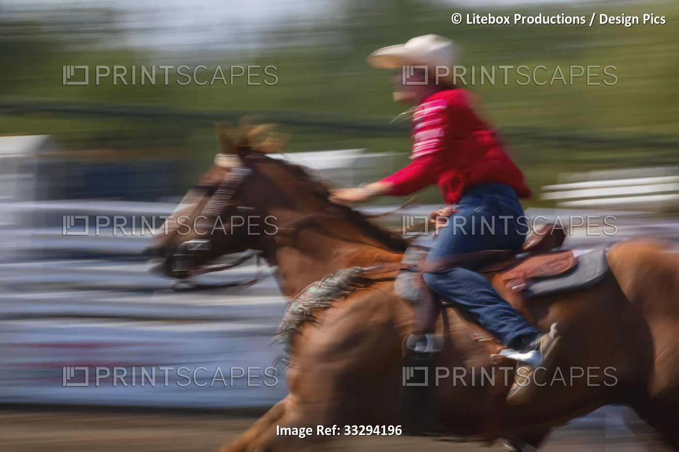 Motion blur of a cowgirl on a horse racing down a track; Alberta, Canada