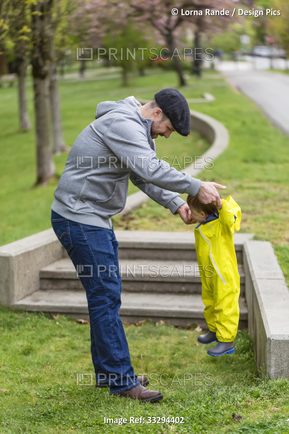 Father playing in the park with his daughter on a spring day, lifting her up in ...