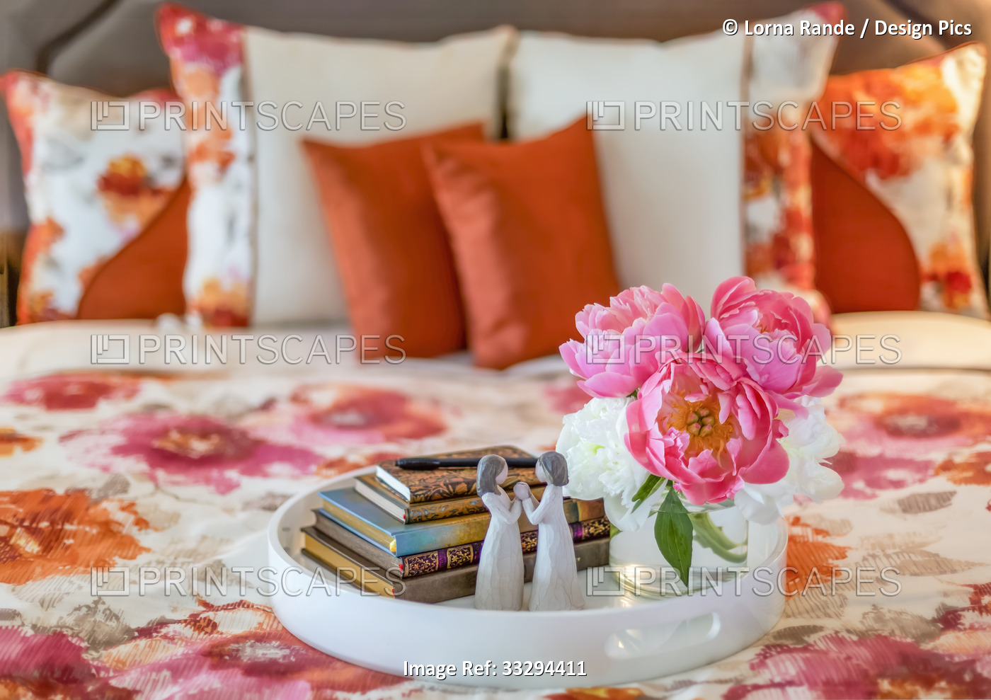 Bouquet of pink and white peonies, small stack of books and figurine on a bed ...