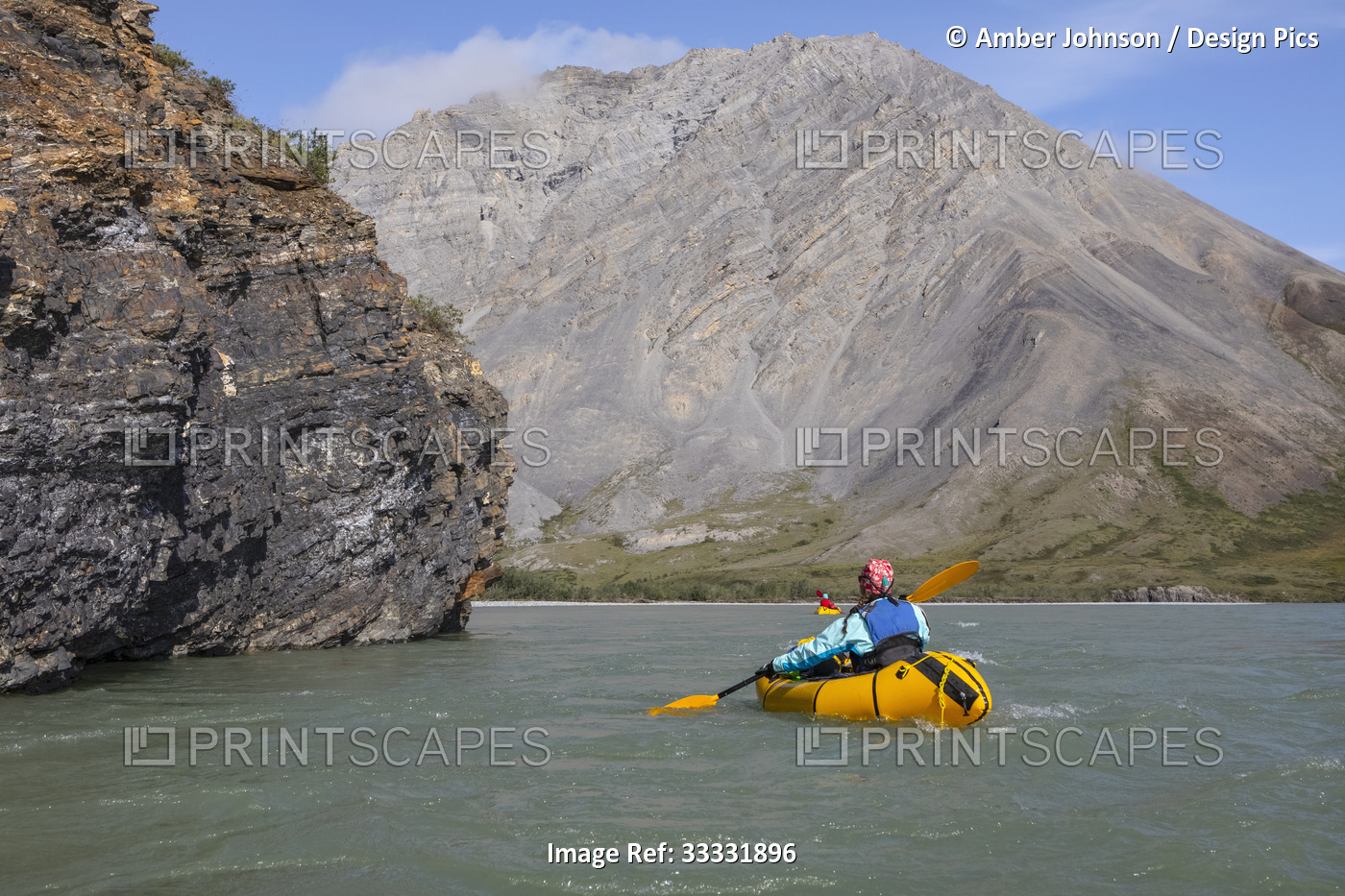 Two women paddling past rock feature on the Canning River in yellow packraft ...