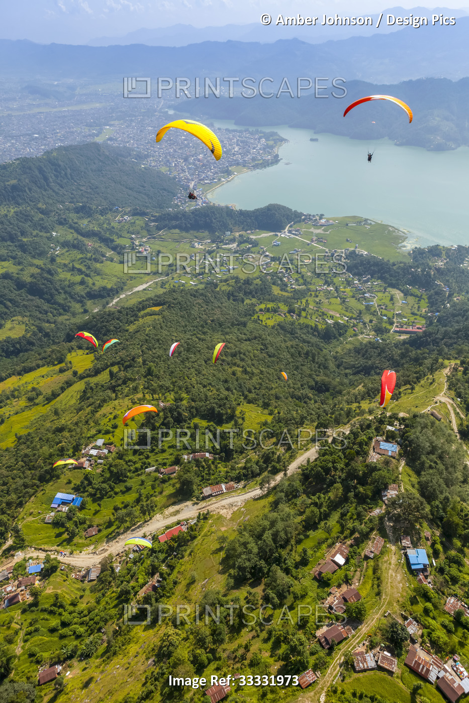 Aerial view of a group of paragliders flying above Sarangkot, playing in the ...