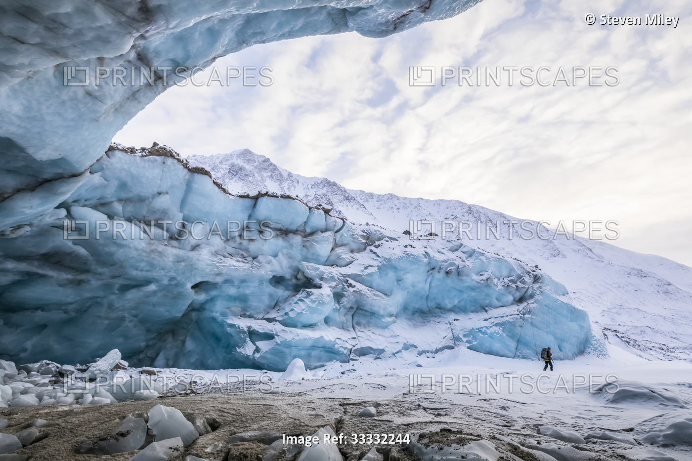 A hiker stands in the entrance of a Black Rapids Glacier ice cave in the ...
