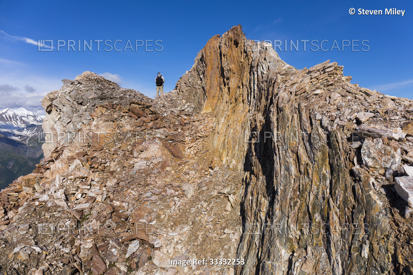 A hiker navigates a rocky ridge in the Eastern Alaska Range; Alaska, United ...