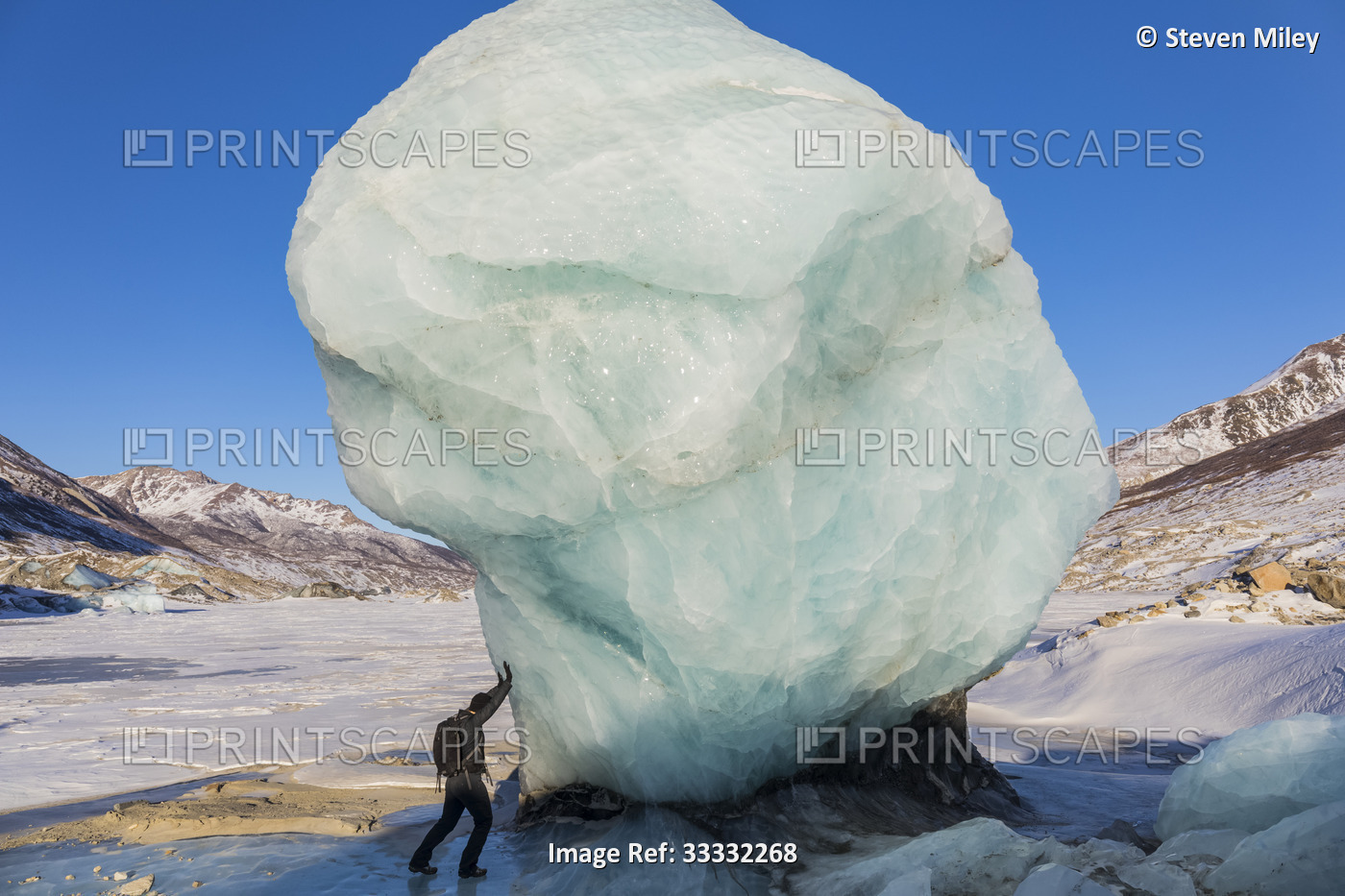 Female hiker pretending to hold back a massive, freestanding chunk of ice at ...