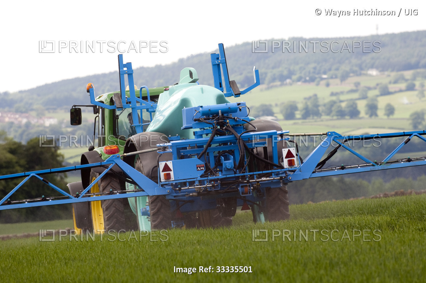 Farmer spraying spring barley crop with herbicide.