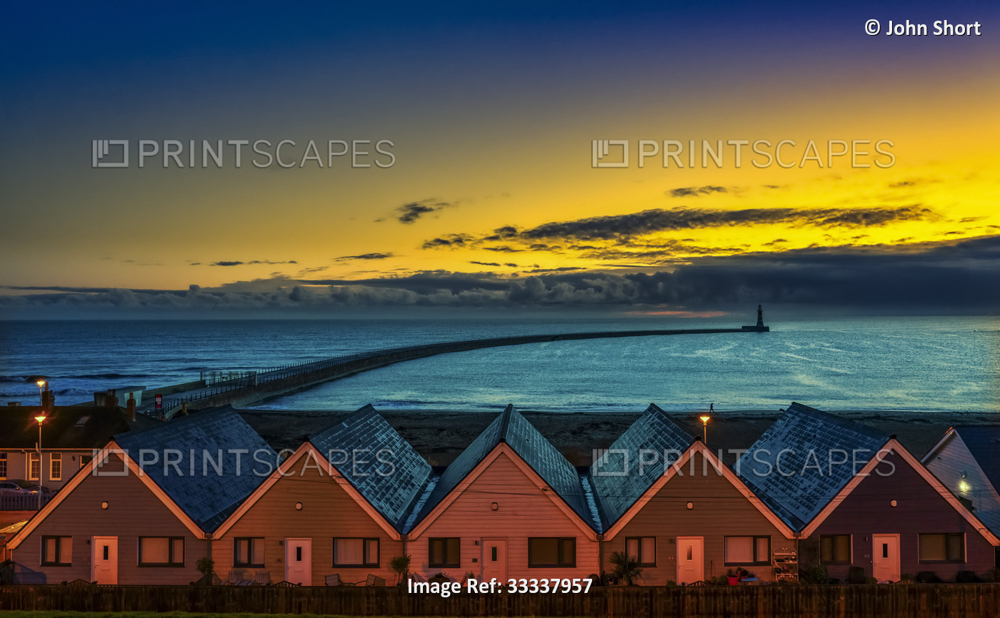 Row of illuminated houses at Roker Beach in Sunderland with a silhouette of the ...