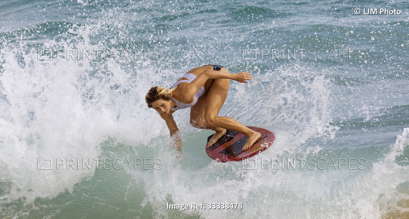 A young professional skimboarder riding a wave at Sandy Beach; Oahu, Hawaii, ...