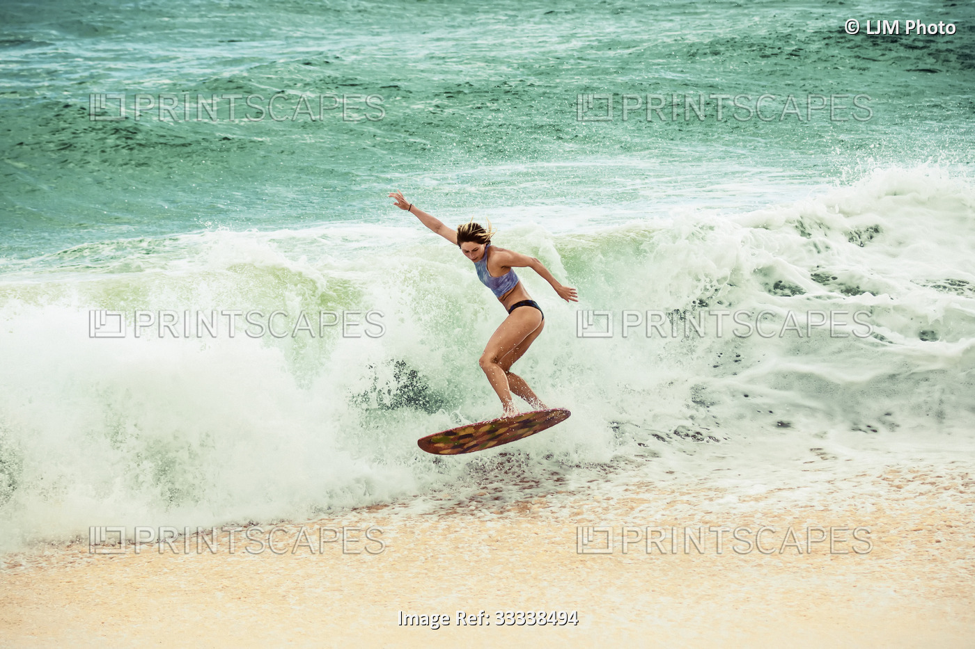 A young professional skimboarder riding a wave at Sandy Beach; Oahu, Hawaii, ...