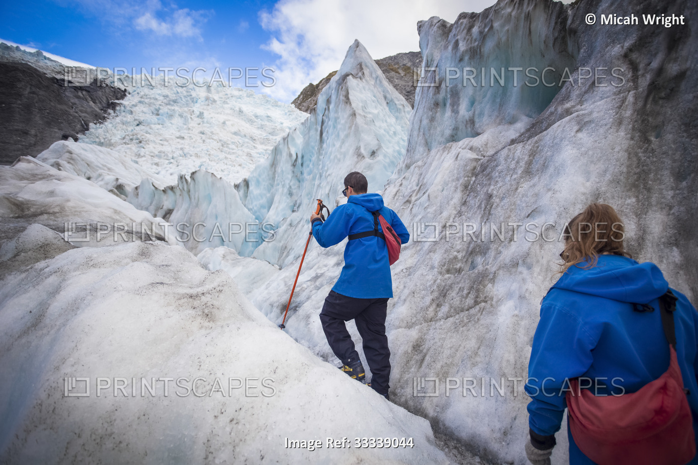 Travelers exploring the famous Franz Josef Glacier with its, blue ice caves, ...