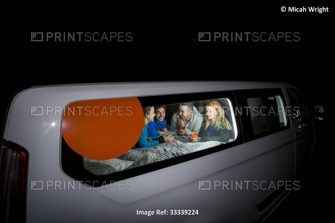 Group of travelers huddled inside their camper van playing games for the ...