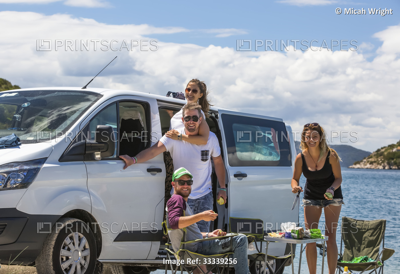 Friends standing next to camper van making lunch as they stop at Slano to enjoy ...