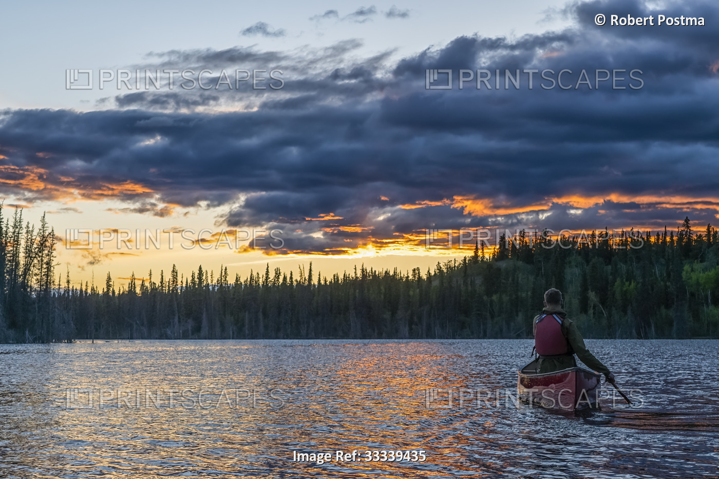 View taken from behind of person canoeing at sunset on a lake near Whitehorse; ...