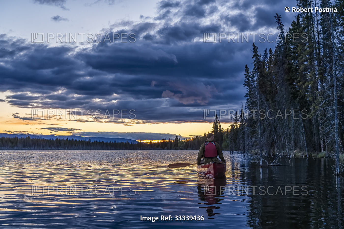 Person canoeing at sunset on a lake near Whitehorse; Yukon, Canada