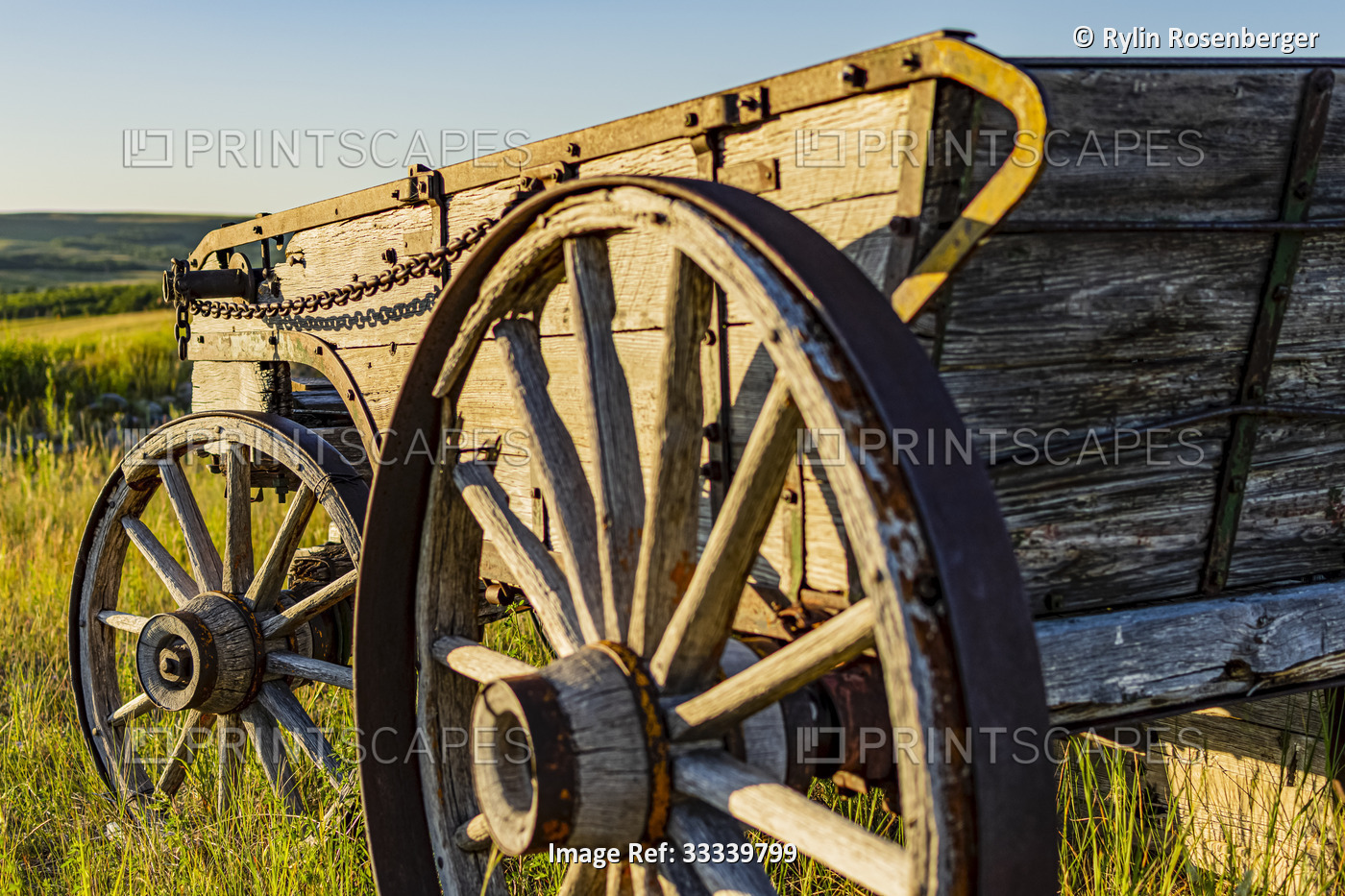 Sunlight reflected on an old wooden wagon sitting in a field; Waterton Lakes ...