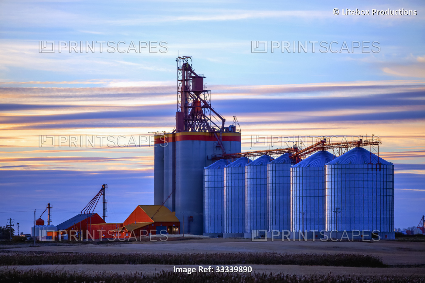 Loading station with grain terminal and grain bins at sunset; Alberta, Canada