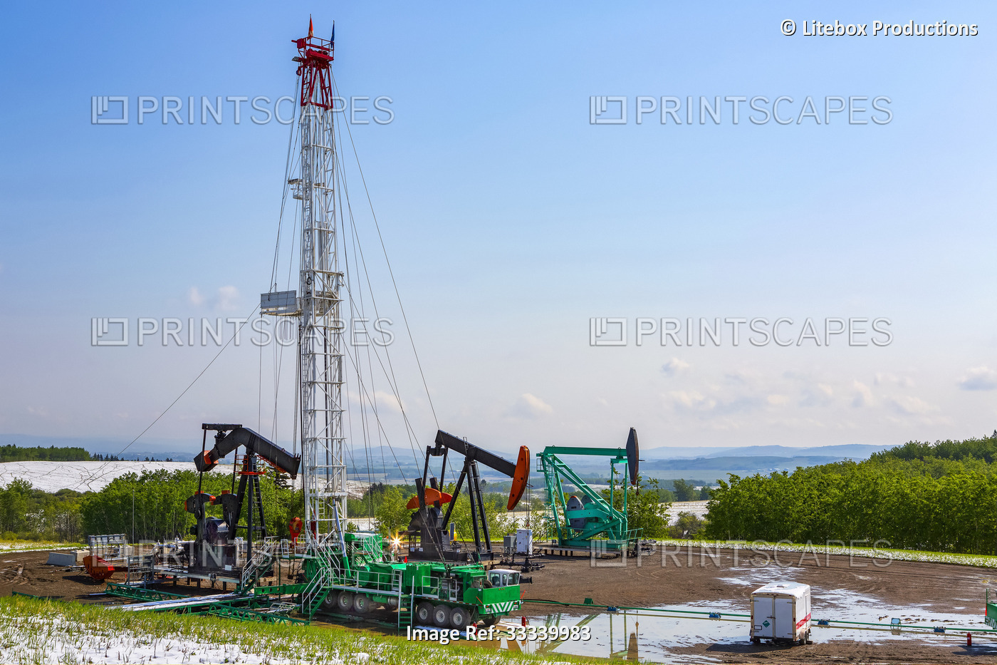 A pumpjacks and triple rig drilling equipment sit in the foothills of the ...