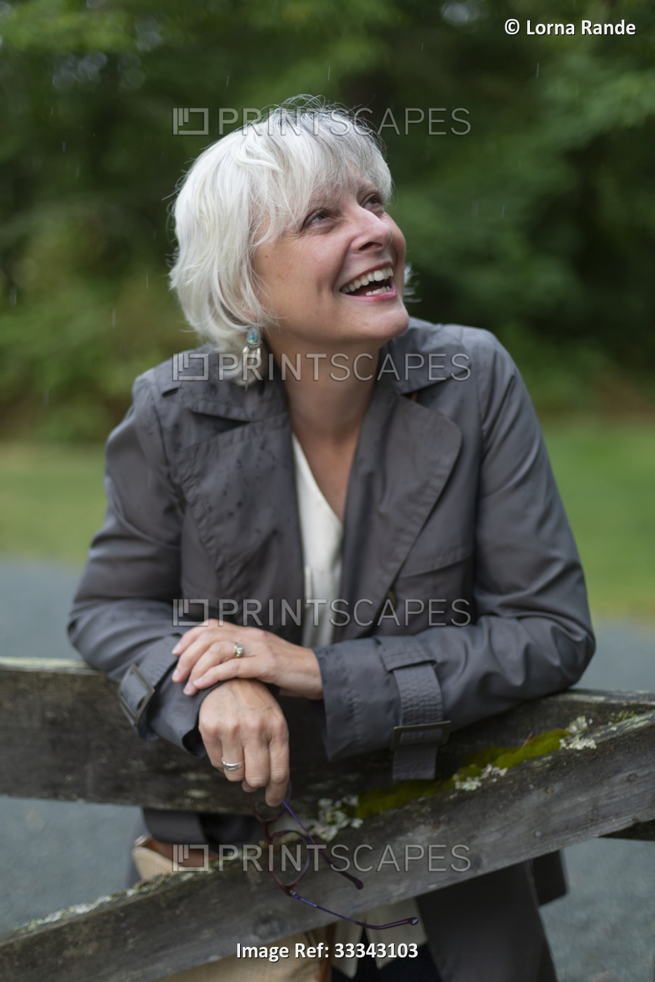 Portrait of a mature woman in casual clothing leaning on a weathered rail and ...