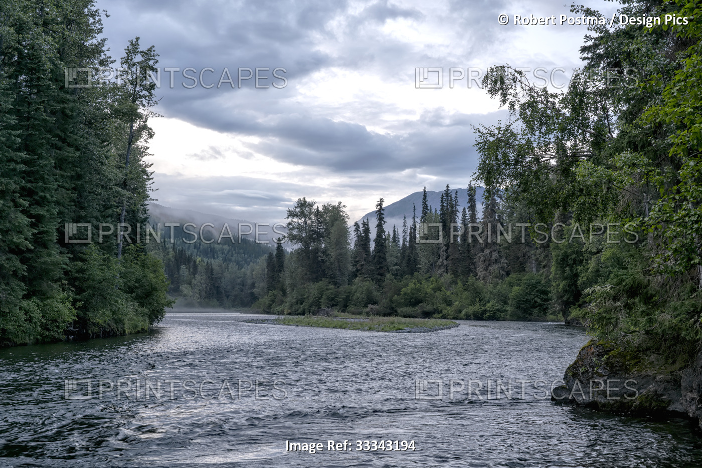 A river flows through a forest with mountains in the distance at dusk; Atlin, ...