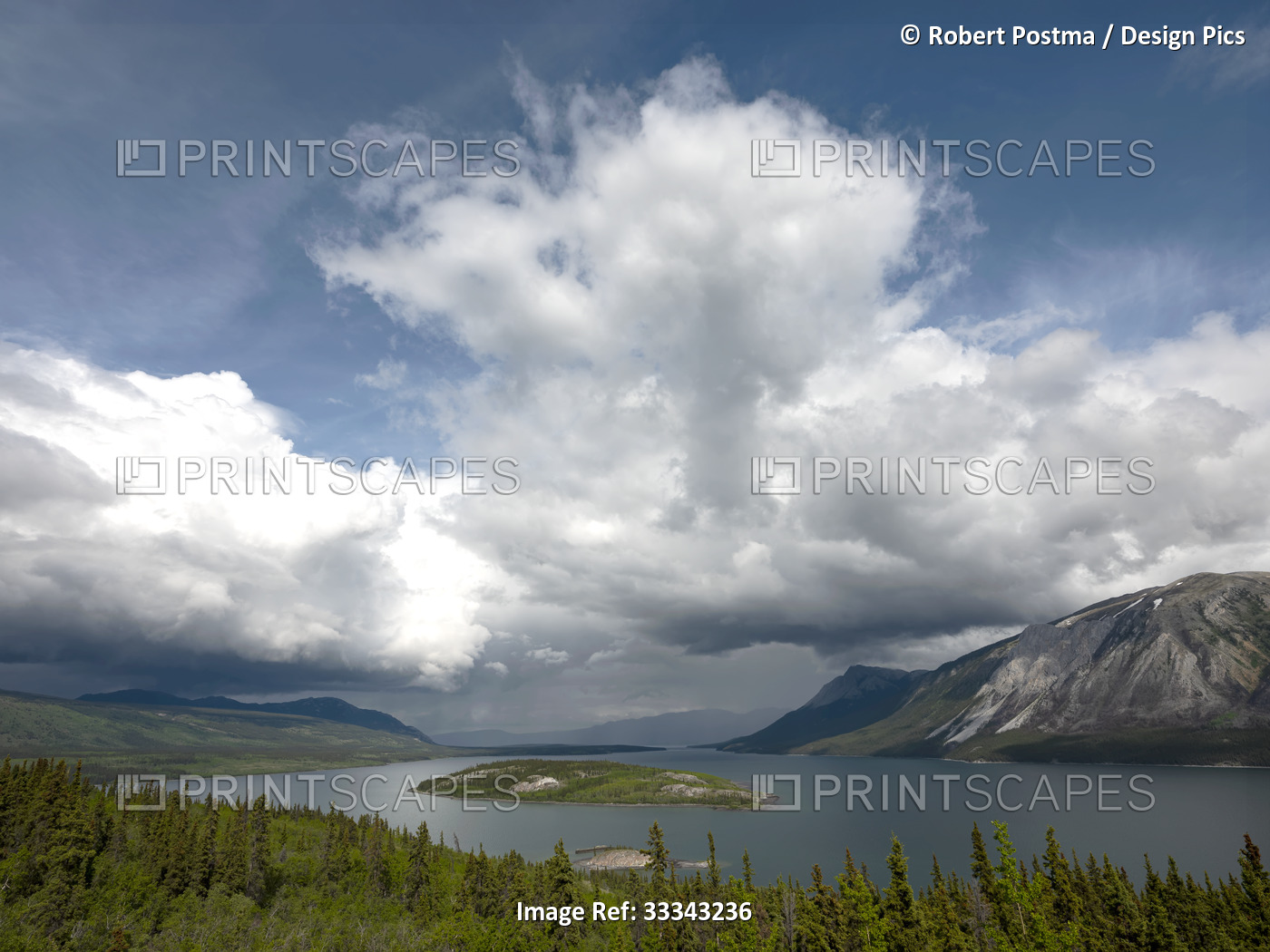 Tranquil lake surrounded by forest and mountains in the Yukon and cloud ...