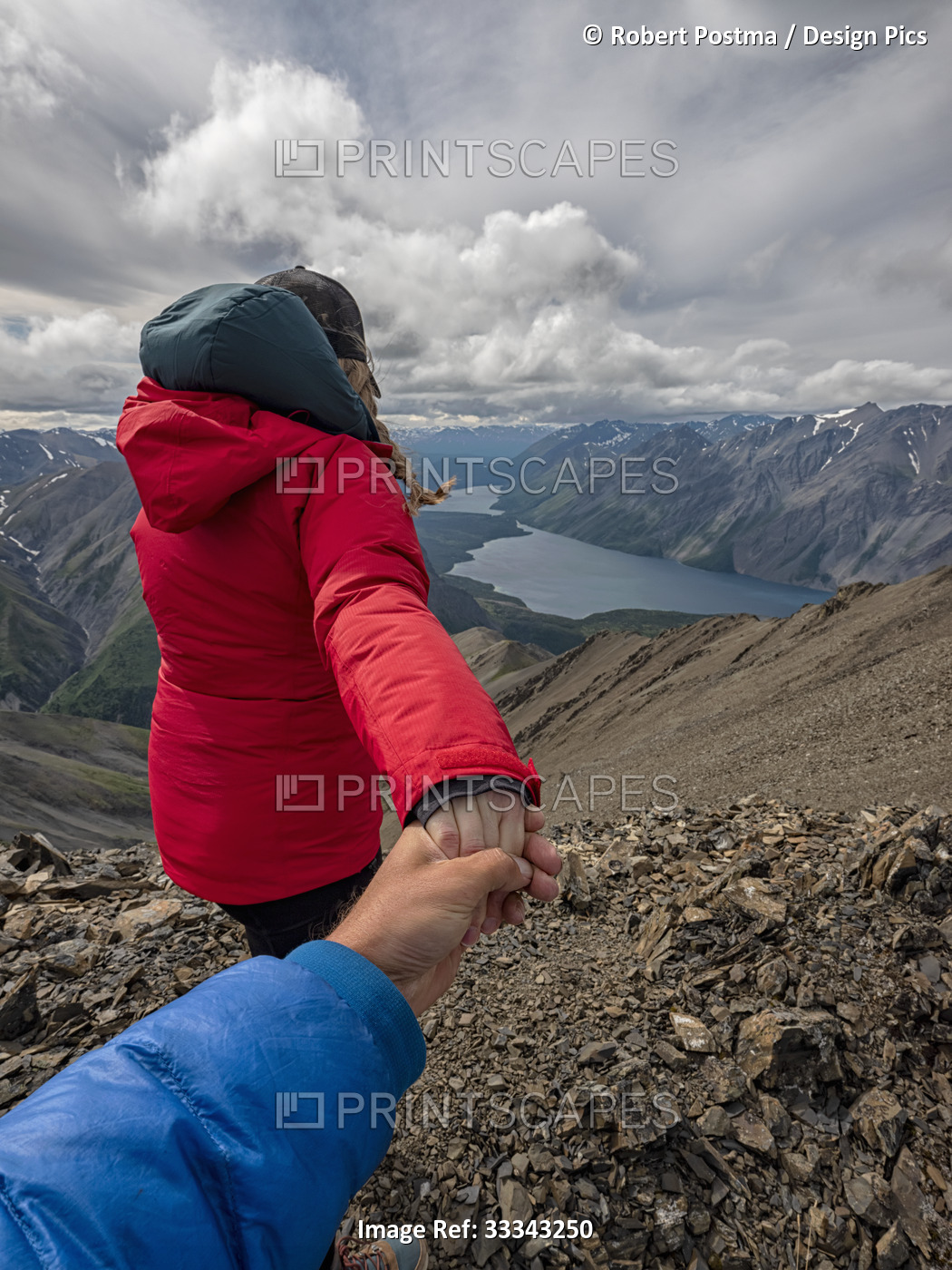 View taken from behind of a woman hiker taking a man by the hand and leading ...