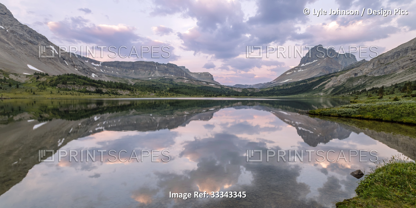 Rocky Mountains reflected in a tranquil Baker Lake at sunset in Banff National ...