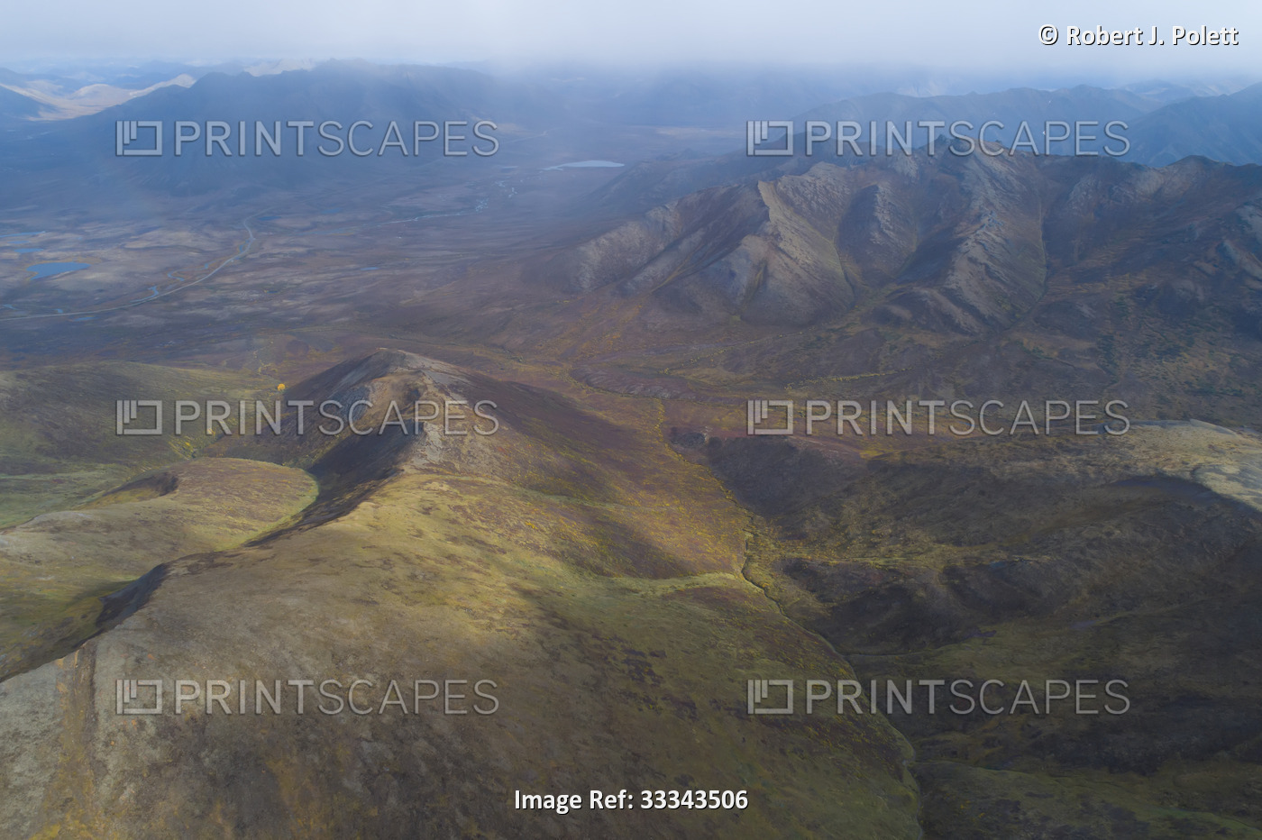 Aerial overview of mountain peaks and rugged landscape in autumn; Dawson City, ...