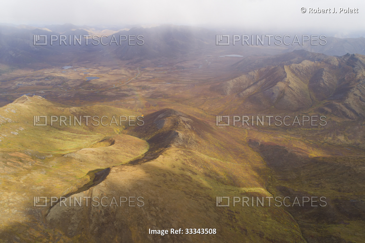 Aerial overview of misty fog over the mountain peaks and rugged landscape in ...