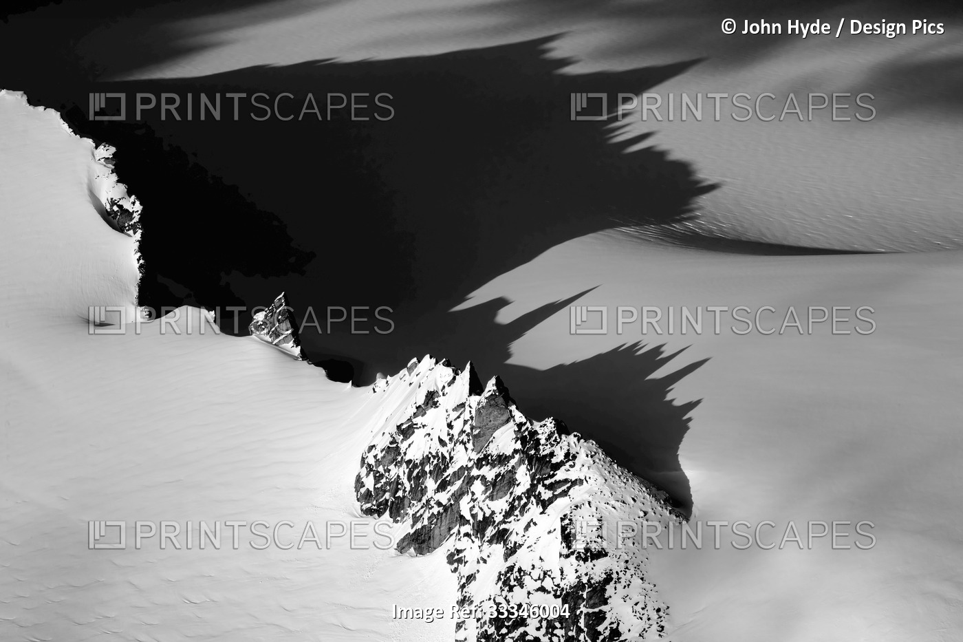 Aerial view of the jagged mountains peaks rising through the snow covered ...
