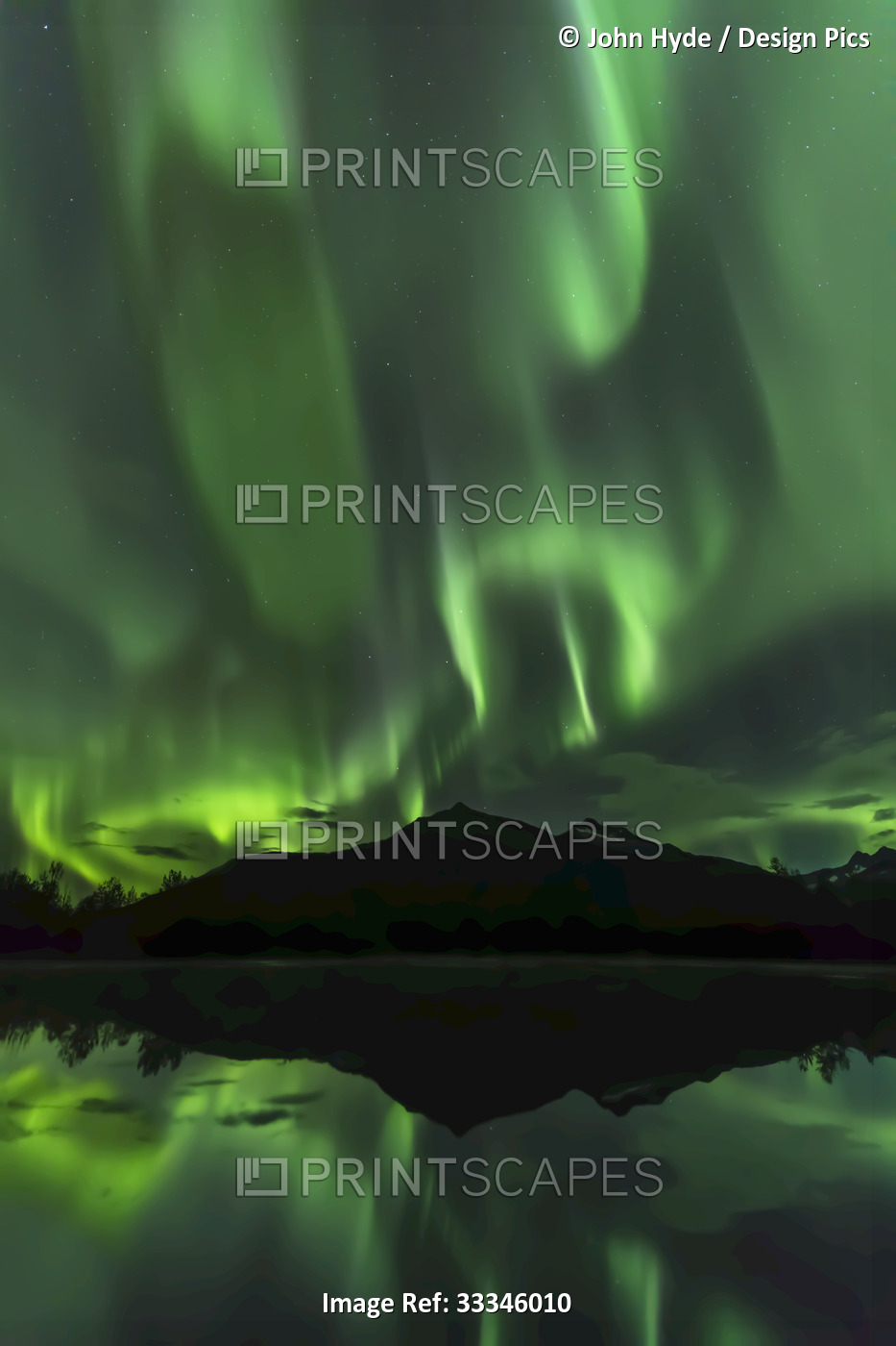 Silhouetted mountains with a green glowing Northern Lights display and the ...