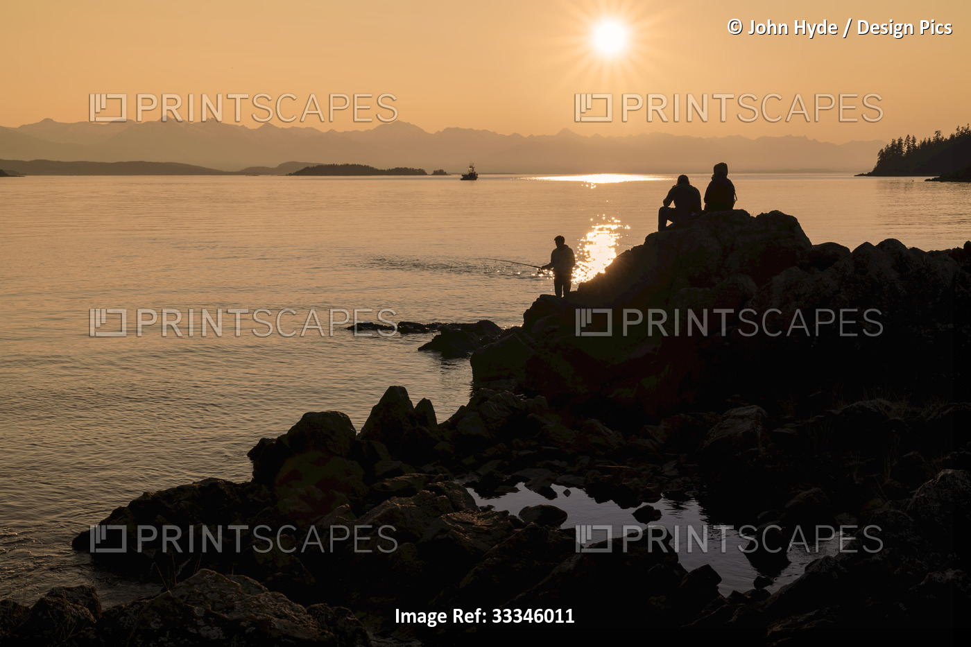 People and rugged shore in silhouette, fishing and enjoying coastal views at ...