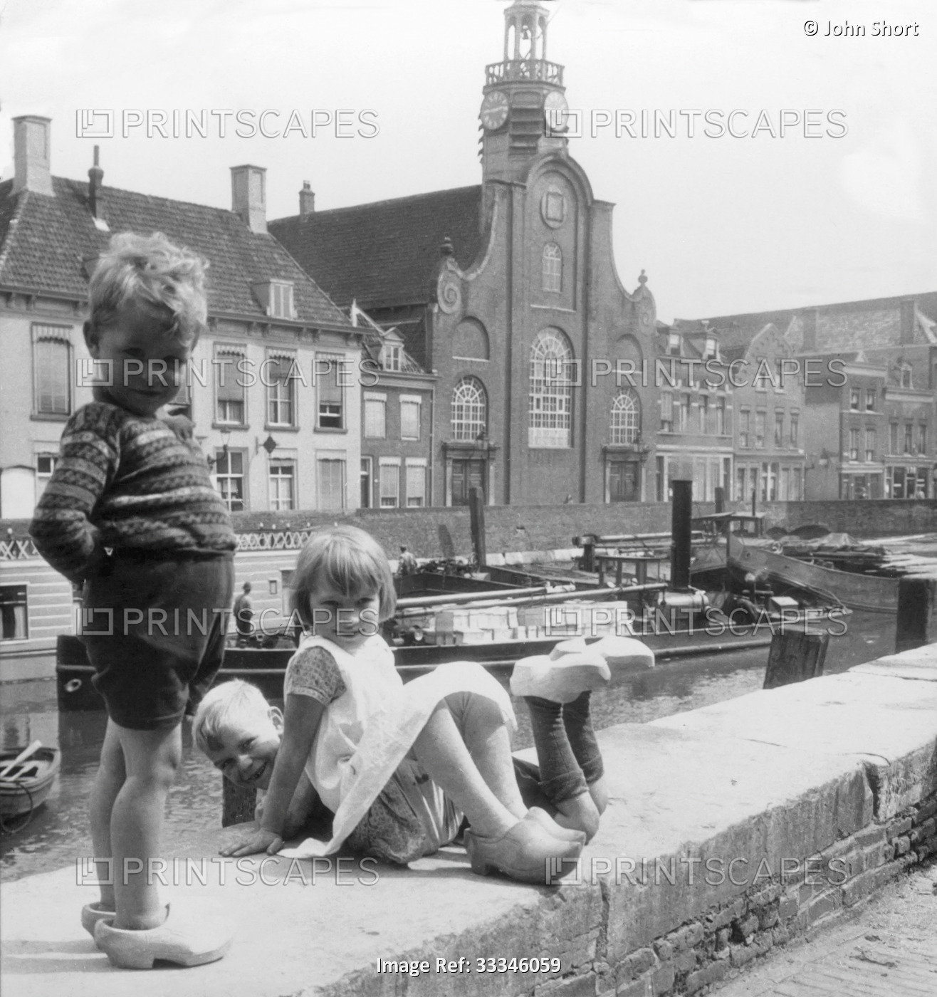 Historic image in black and white of children playing together along the canal ...