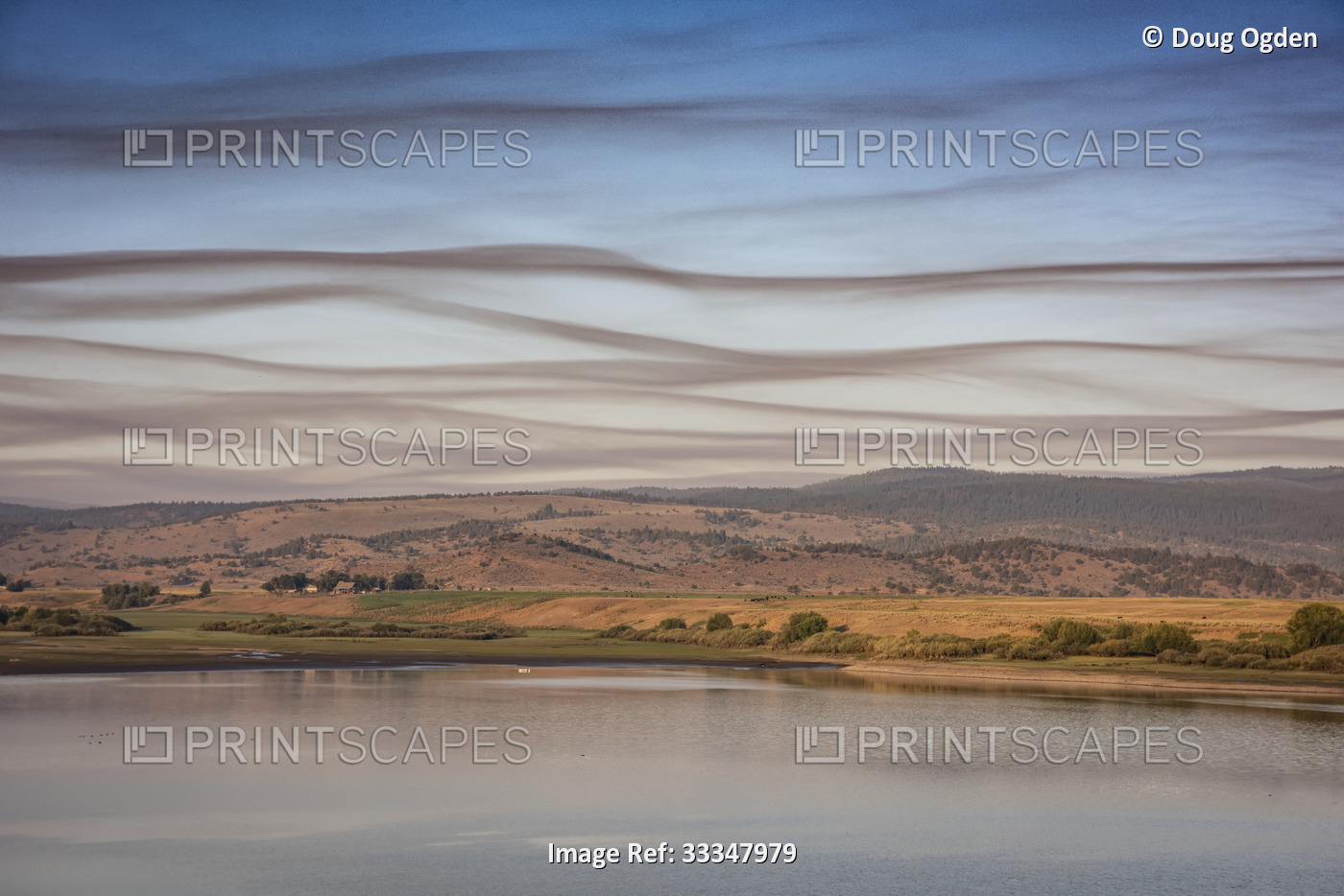 Linear smoke clouds cross the morning sky over Unity Reservoir at the Unity ...