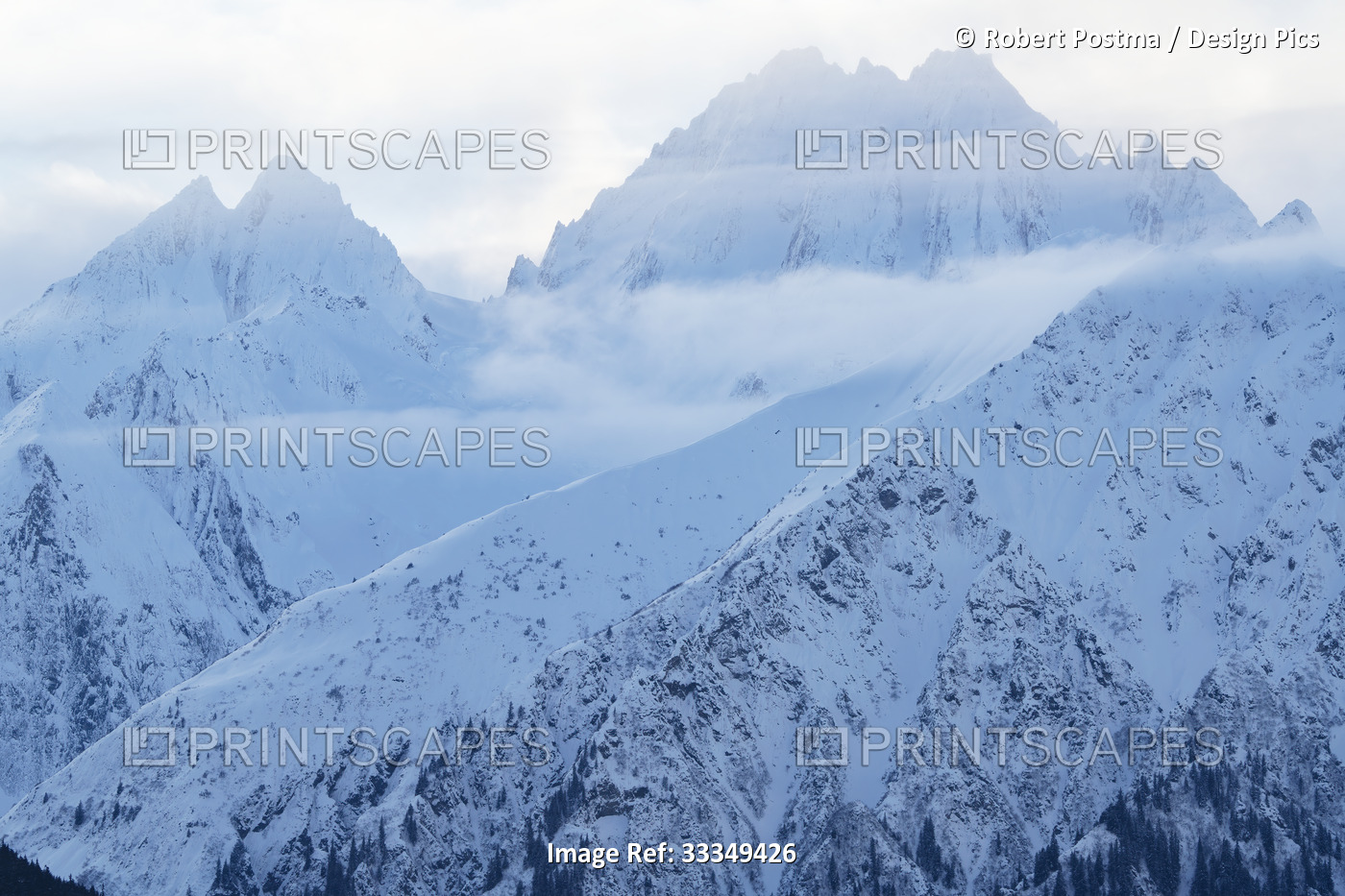 Close-up of the majestic snow covered mountain tops with misty clouds in the ...