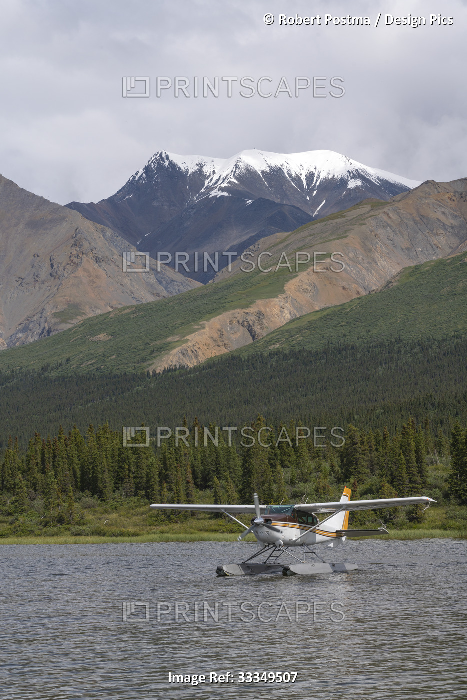 Floatplane on the water resting near the shore of a lake with forested and ...