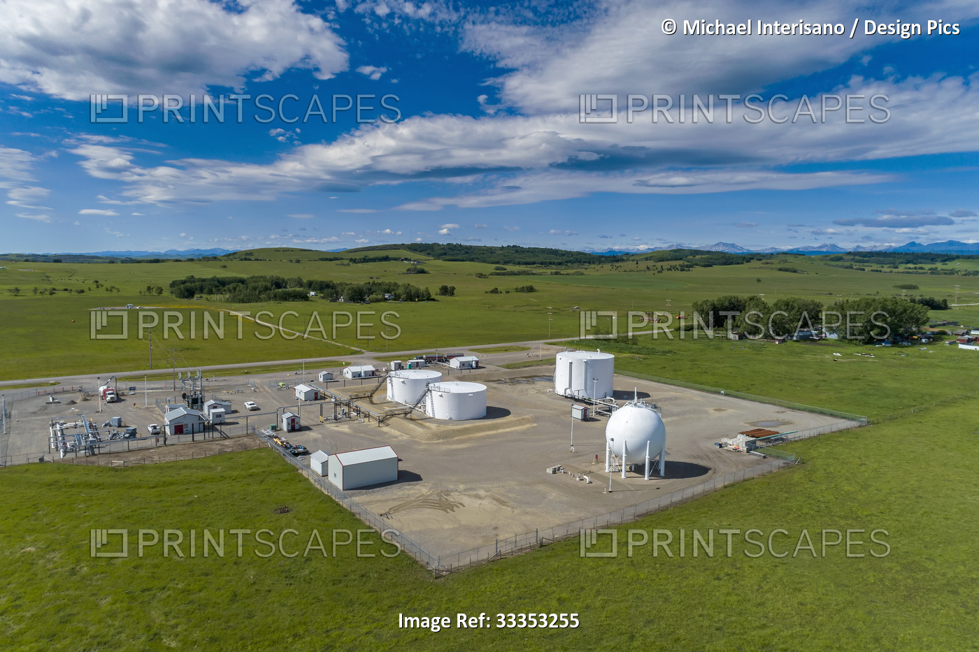 Aerial view of a oil storage site with large white storage tanks with blue sky ...