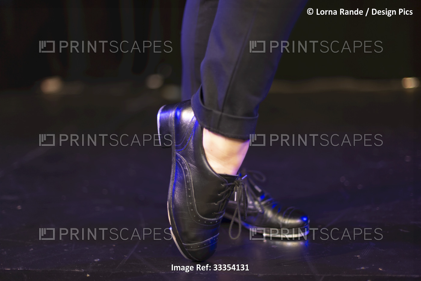 Close-up of tap shoes on a tap dancer, posing on a black floor; Langley, ...
