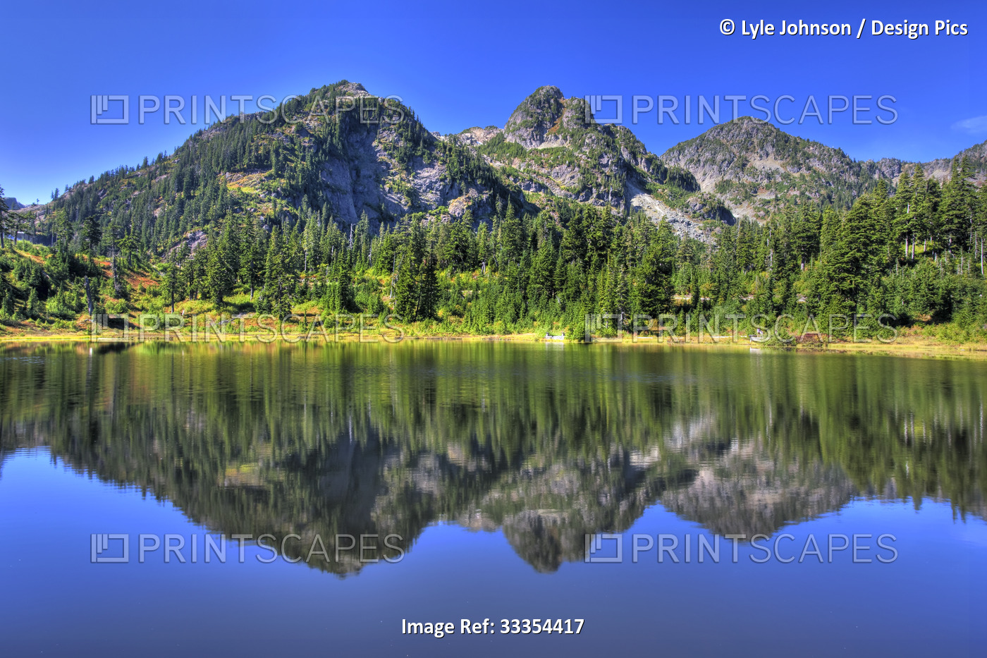 Mirror image of mountains and bright blue sky reflected in a lake, Mount Baker ...
