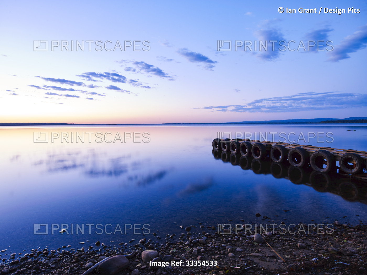 Glowing horizon at sunset reflected in tranquil water of Gregoire Lake with a ...